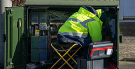 Man fixing telephone cables at box on street